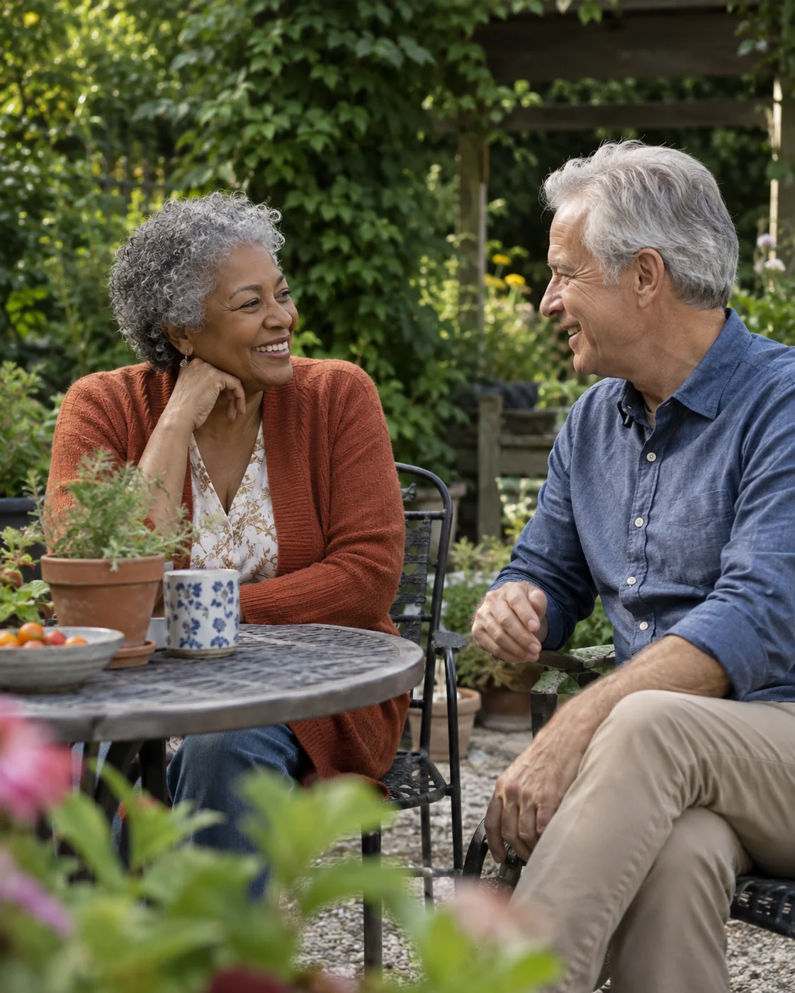 Two older adults sharing a relaxed conversation in a sunlit garden.